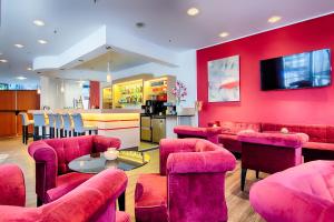 a restaurant with pink chairs and a table and a counter at ACHAT Hotel Bochum Dortmund in Bochum