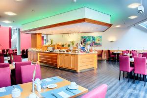 um restaurante com cadeiras e mesas cor-de-rosa e um buffet em ACHAT Hotel Bochum Dortmund em Bochum