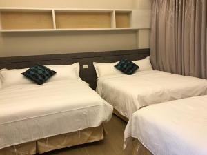 馬公市的住宿－好窩民宿，配有白色床单和黑色枕头的客房内的两张床