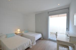 a white bedroom with two beds and a window at Bellavista - Ref. 029 in Begur
