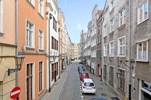 a narrow street with cars parked on the sides of buildings at Dom & House - Apartments Old Town Powroznicza in Gdańsk