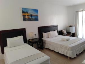 a bedroom with two beds and a desk and a window at Boracay White Coral Hotel in Boracay