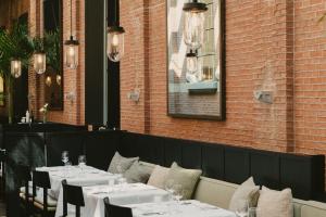 un restaurant avec des tables et des chaises blanches et un mur en briques dans l'établissement august, à Anvers 37 autres photos