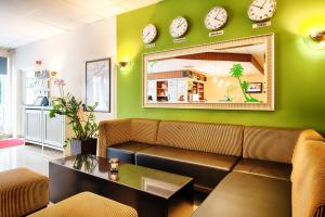a living room with a couch and clocks on the wall at ACHAT Hotel Chemnitz in Chemnitz