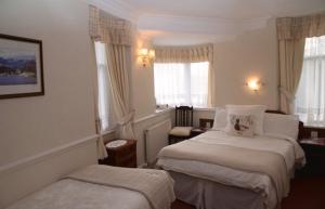 Habitación de hotel con 2 camas y 2 ventanas en Windermere Lynwood Guest House, en Windermere