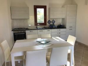 een keuken met een witte tafel en witte stoelen bij Corallo in San Teodoro