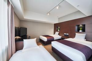 a hotel room with two beds and a television at HOTEL MYSTAYS Shimizu in Shizuoka