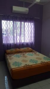 a bed in a purple room with a window at Cottage Muslim Homestay ByWawaSha in Tanjung Malim