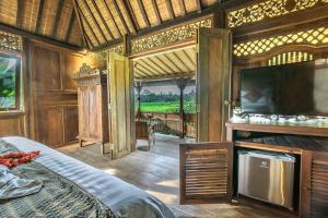 a bedroom with a bed and a tv in a room at Malaya Villas Ubud in Ubud