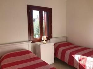 een slaapkamer met twee bedden en een raam bij Corallo in San Teodoro