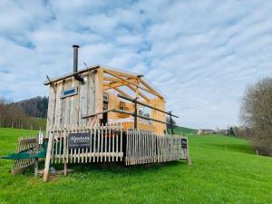 una pequeña casa de madera en un campo con una valla en Hof Dietrich, en Herisau