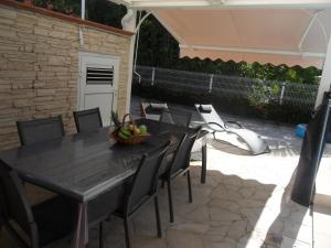 a black table and chairs with a bowl of fruit on it at Le Coin Tranquille in Sainte-Anne