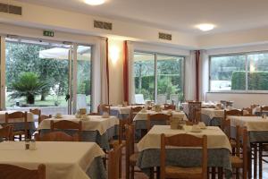 a dining room with tables and chairs and windows at Hotel Villa Verde in Nago-Torbole