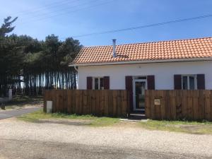 une petite maison blanche avec une clôture en bois dans l'établissement Maison à deux pas de l'océan, à Biscarrosse-Plage