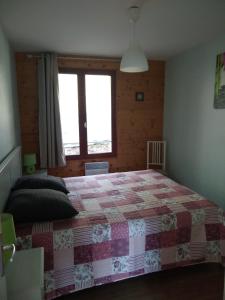 ein Schlafzimmer mit einem Bett mit einer Decke darauf in der Unterkunft Appartement Les marmottes in Ilhan