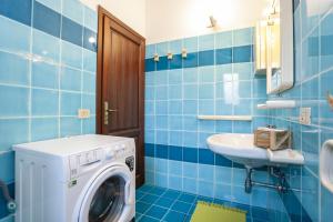 a blue tiled bathroom with a washing machine and a sink at Villino Funtana Bilo in San Teodoro