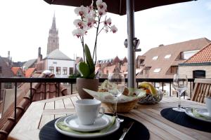 a table on a balcony with a cup of coffee and flowers at House Loppem 9-11 in Bruges