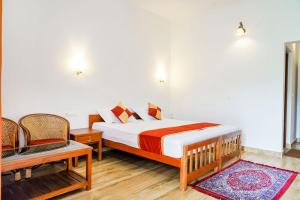 een slaapkamer met een bed en 2 stoelen. bij Wild Mist Homestay in Munnar