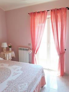 Schlafzimmer mit einem Bett mit rosa Vorhängen und einem Fenster in der Unterkunft La mia dolce casa in Mascali