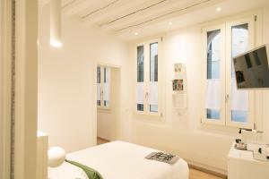 Habitación blanca con cama y TV en San Marco Design Suites, en Venecia