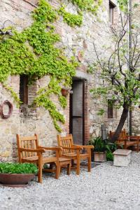 three wooden benches sitting in front of a building at Agriturismo Il Rigo in San Quirico dʼOrcia