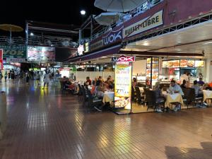 gente sentada en las mesas de un centro comercial por la noche en Lovely 2 bedroom house with private garden, en Mogán