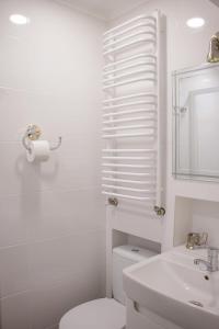 a white bathroom with a toilet and a sink at Antique Lviv in Lviv