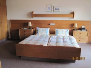 a bedroom with a large bed with a wooden headboard at Berghaus Wastel in Bad Kleinkirchheim