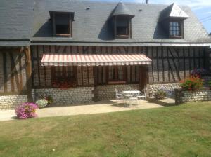 a house with a patio and a table in the yard at Chambres d'Hôtes Le Pressoir in Saint-Martin-de-Boscherville