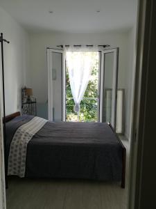 a bedroom with a bed and a large window at Gîtes LA Brunette in Beausoleil