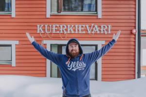a man standing in front of a red building at Kuerkievari KuerHostel in Äkäslompolo