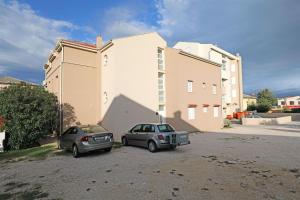 two cars parked in a parking lot in front of a building at Apartments Karolina in Novalja