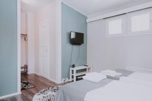 1 dormitorio blanco con 1 cama y TV en Kuerkievari KuerHotel en Äkäslompolo