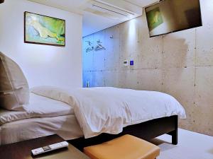 西歸浦的住宿－Hotel Stay Interview Jeju，卧室配有一张床,墙上配有电视。