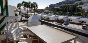 Una mesa y sillas en un balcón con vista a una ciudad. en Lovely 2 bedroom house with private garden, en Mogán