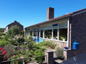 a brick house with a garden with flowers at B&B De Blauwe Tulp in Noord-Scharwoude