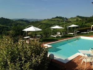 una piscina con ombrelloni, tavoli e sedie di Locanda Gli Ulivi a Monteveglio