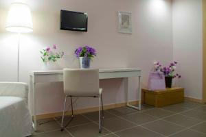 a room with a desk with flowers and a tv at Palazzo Mulada in Frattamaggiore