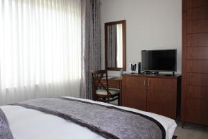 a bedroom with a bed and a tv and a desk at Lavender Boutique Hotel in Ramallah