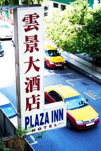 zwei Autos auf einem Parkplatz mit einem Pizza-Gastschild geparkt in der Unterkunft Plaza Inn in Sibu