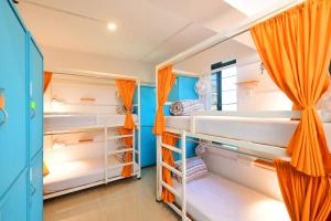 a room with white bunk beds with orange curtains at goSTOPS Mumbai in Mumbai