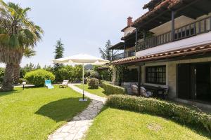 a patio with an umbrella next to a house at #FLH - Coconut & Vanilla & Pineapple Pool Apartments in Kriopigi