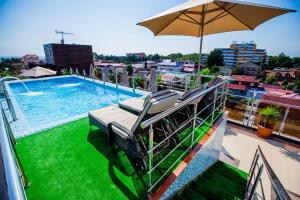balcón con piscina y sombrilla en Shine House Hotel, en Adler