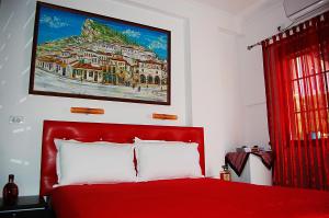 a bedroom with a red bed with a painting on the wall at Buda Apartment in Berat
