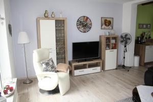 a living room with a flat screen tv and chairs at Fewo Lirich in Oberhausen