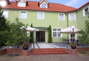 a green house with a patio and umbrella at Park Hotel in Rzepin