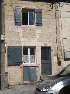 a building with green doors and a car parked in front at L'Inattendue in Chaumont