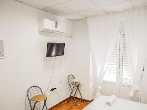 Biały pokój z 2 krzesłami i telewizorem na ścianie w obiekcie Estudio Calle Murillo w Sewilli +4 zdjęcia