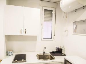 biała kuchnia ze zlewem i oknem w obiekcie Estudio Calle Murillo w Sewilli