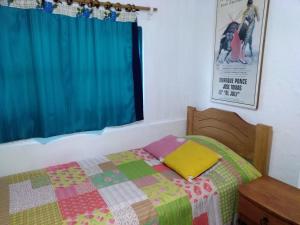 a bedroom with a bed with a quilt and a window at Hostal Buena Vista in San Antonio